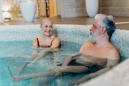 Free Smiling senior couple relaxing together in an indoor spa pool, enjoying leisure time. Stock Photo