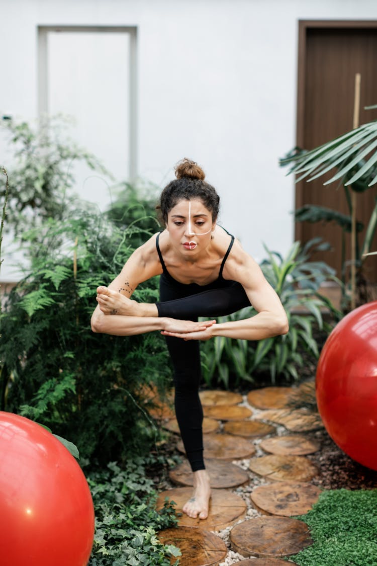 Woman In Black Spaghetti Top And Black Leggings On A Yoga Pose