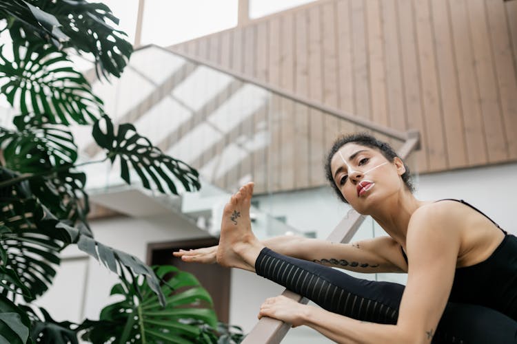 Woman Stretching Her Leg On A Handrail At Home 