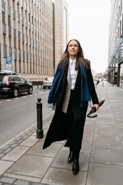 Free Confident woman in business attire walking on city street holding umbrella. Stock Photo