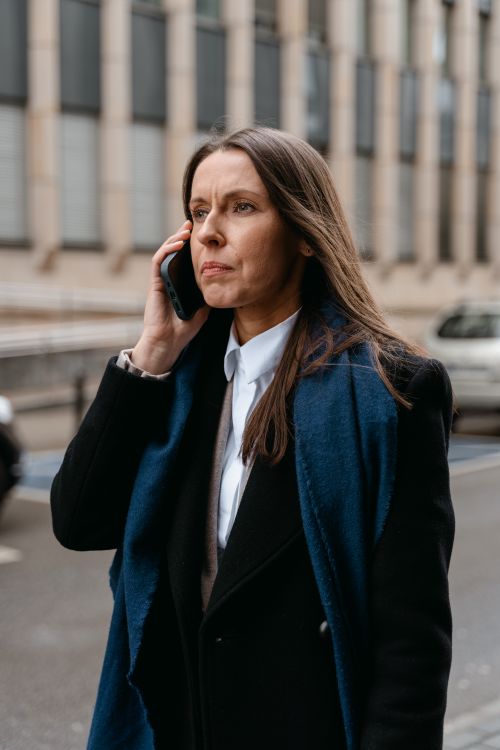 Free Confident woman in business attire talking on phone while walking in urban setting. Stock Photo