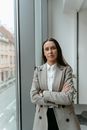 Woman in Gray Coat Standing Beside Glass Window