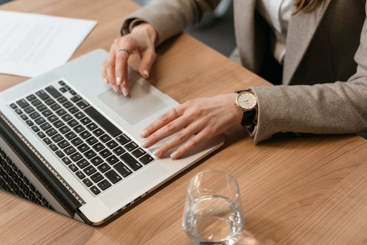 Person Using A Laptop On Wooden Table Top