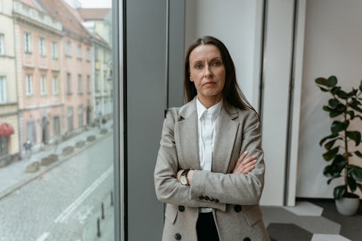 Businesswoman in formal attire by a window, showcasing confidence and professionalism.