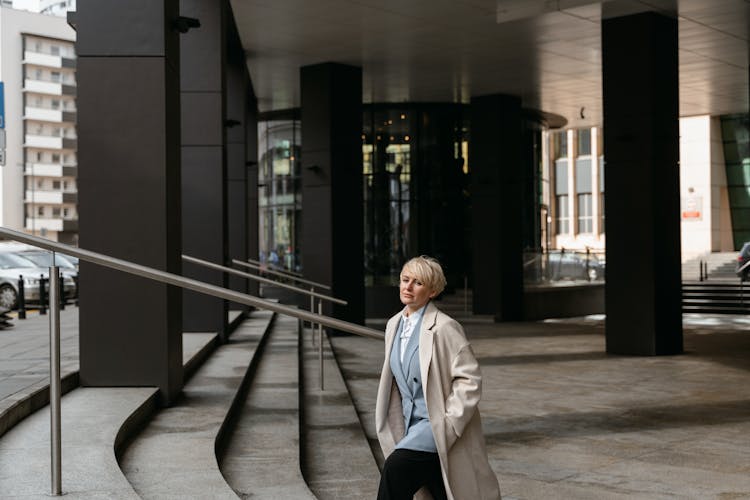 A Woman In White Coat Walking Up The Stairs