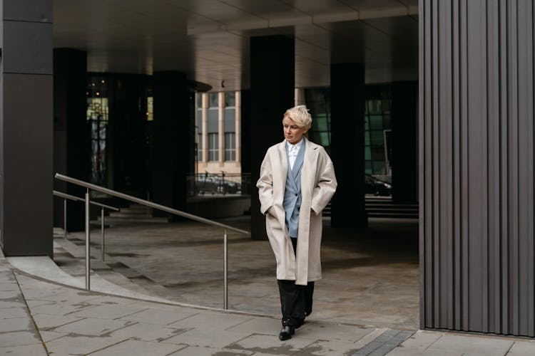 A Woman In White Coat Walking On The Street