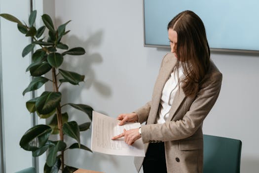 Professional woman in a brown blazer reviewing a document in an office setting.