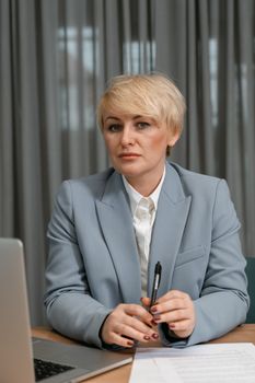 Confident businesswoman with short hair in a blue blazer working at her desk.