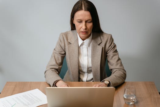 Focused businesswoman working on a laptop at her desk in an office setting.