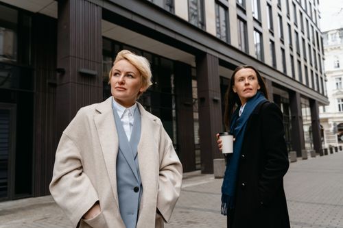 Free Two women in stylish professional attire walking in a modern urban environment. Stock Photo