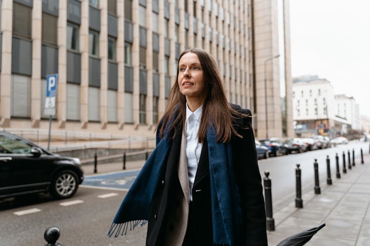 A Woman In Black Blazer Walking On The Sidewalk