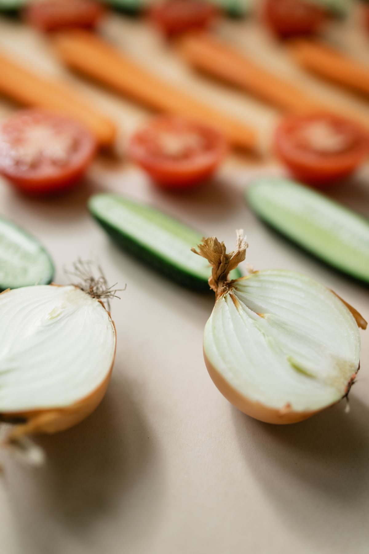 Fresh cucumber, tomato, carrot and onion laid out in rows, the everyday food choices lifestyle counselling works through.