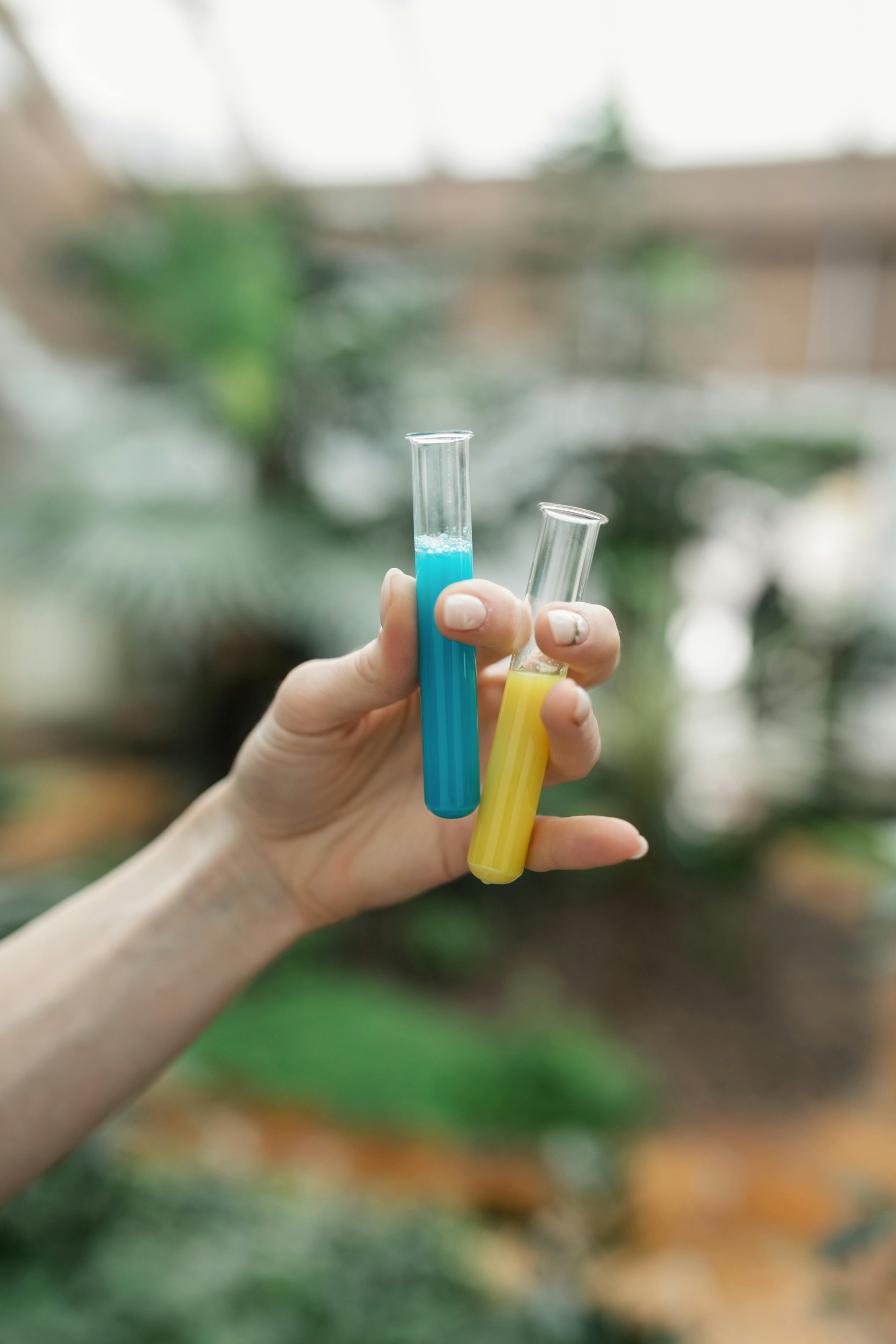 hands holding tubes with colorful substances