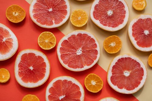 Free Bright and juicy slices of grapefruit and orange arranged on a bold, colorful background, highlighting freshness and nutrition. Stock Photo