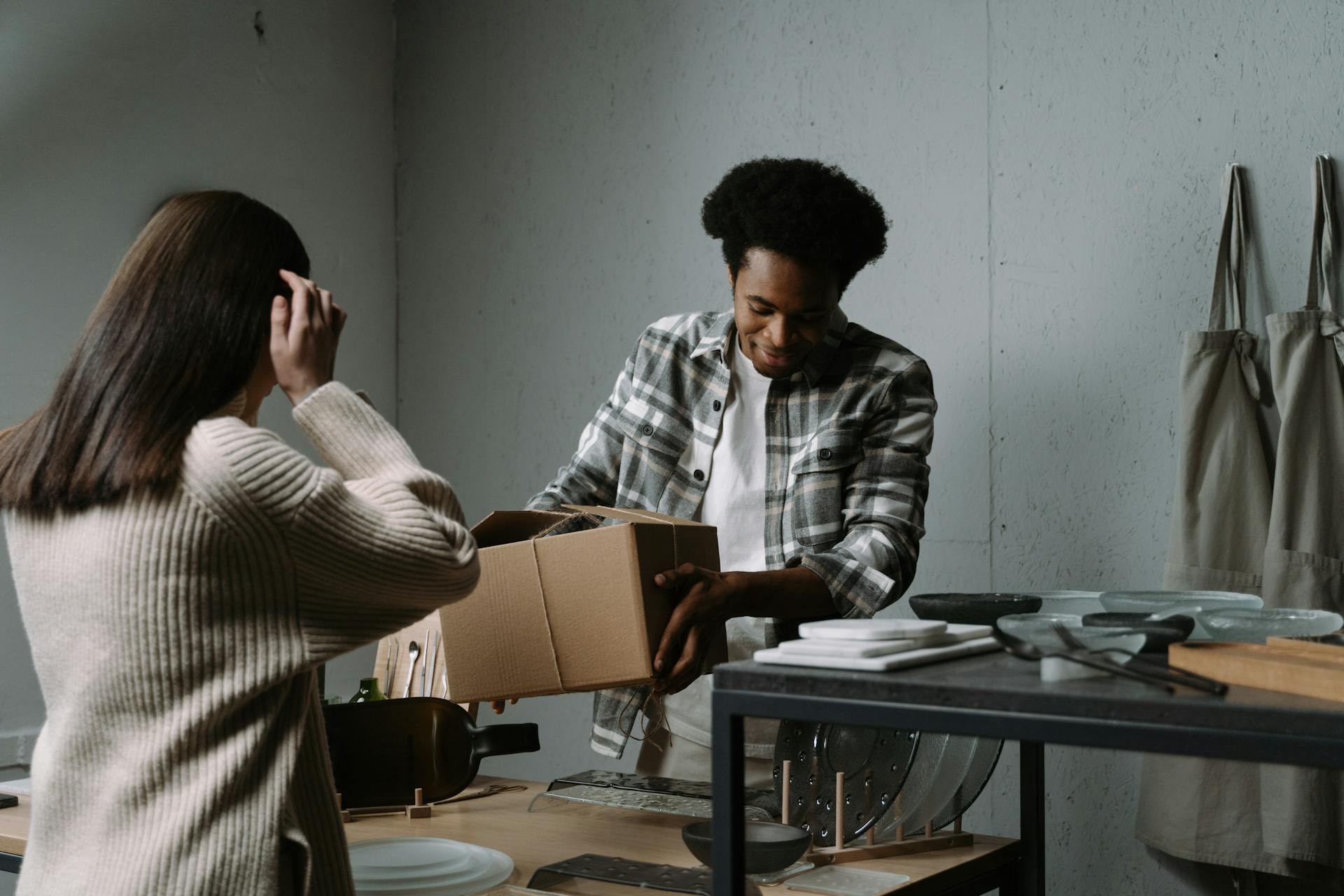 Two people packing kitchenware in a store setting. Diverse, inclusive teamwork indoors.