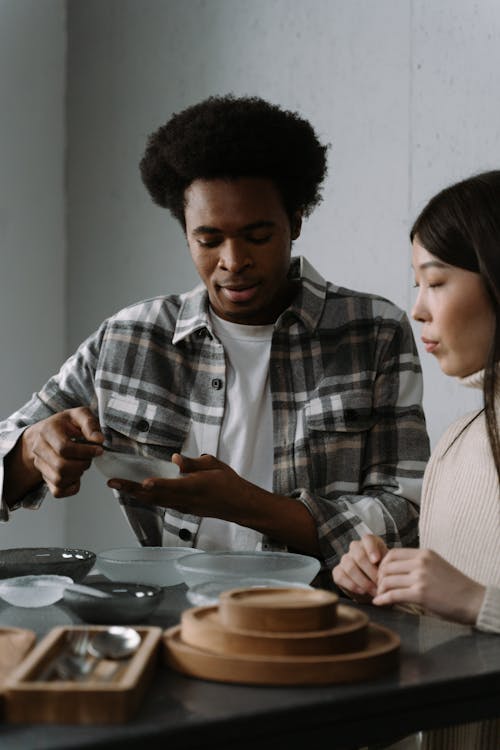 Free Photo of a Man in a Plaid Shirt Selling Dishware to a Woman Stock Photo