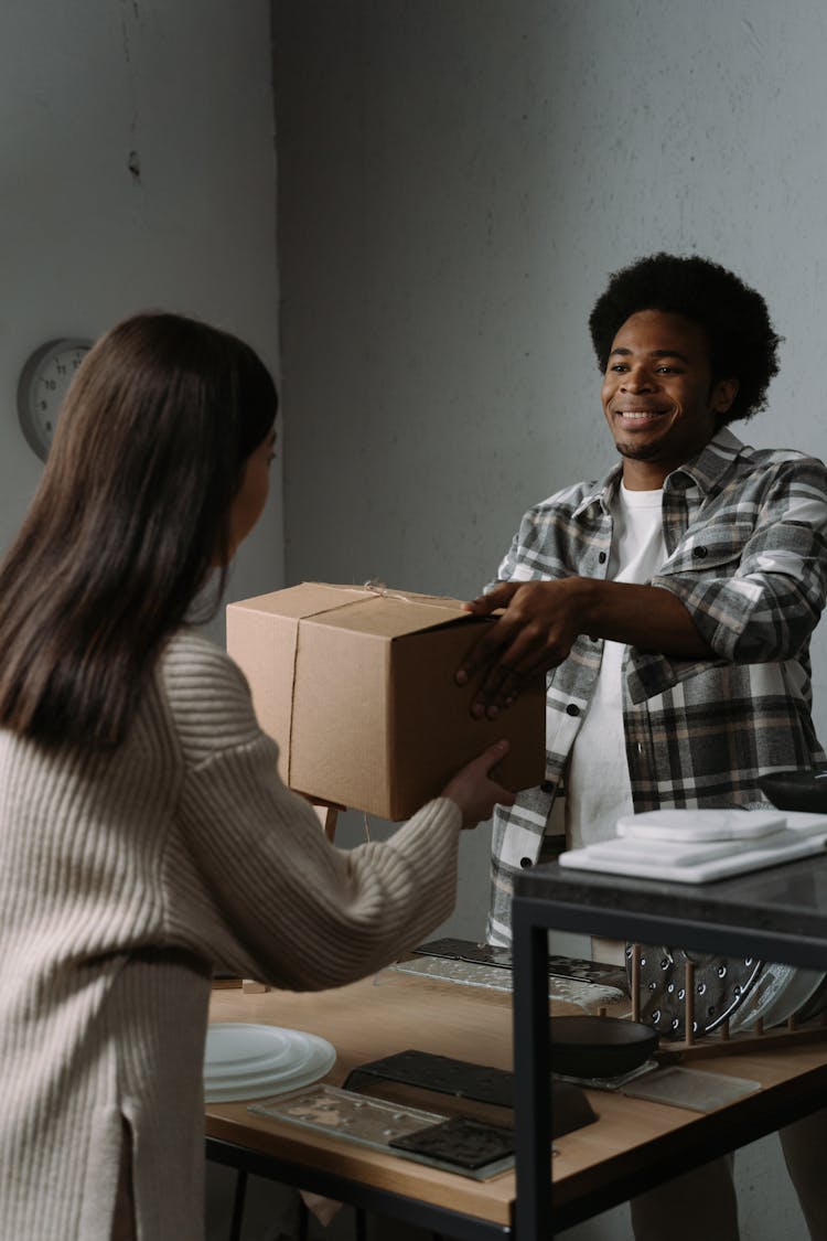 Photo Of A Man Handing Over A Box To A Woman