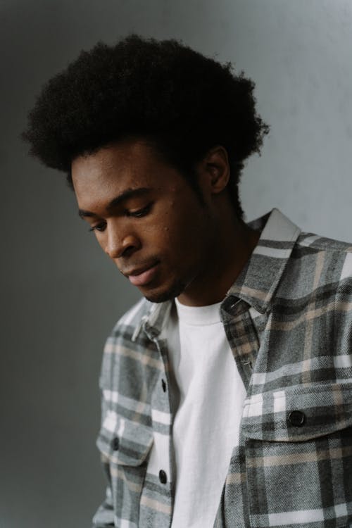 Free Close-Up Shot of an Afro-Haired Man in Checkered Shirt Looking Down Stock Photo