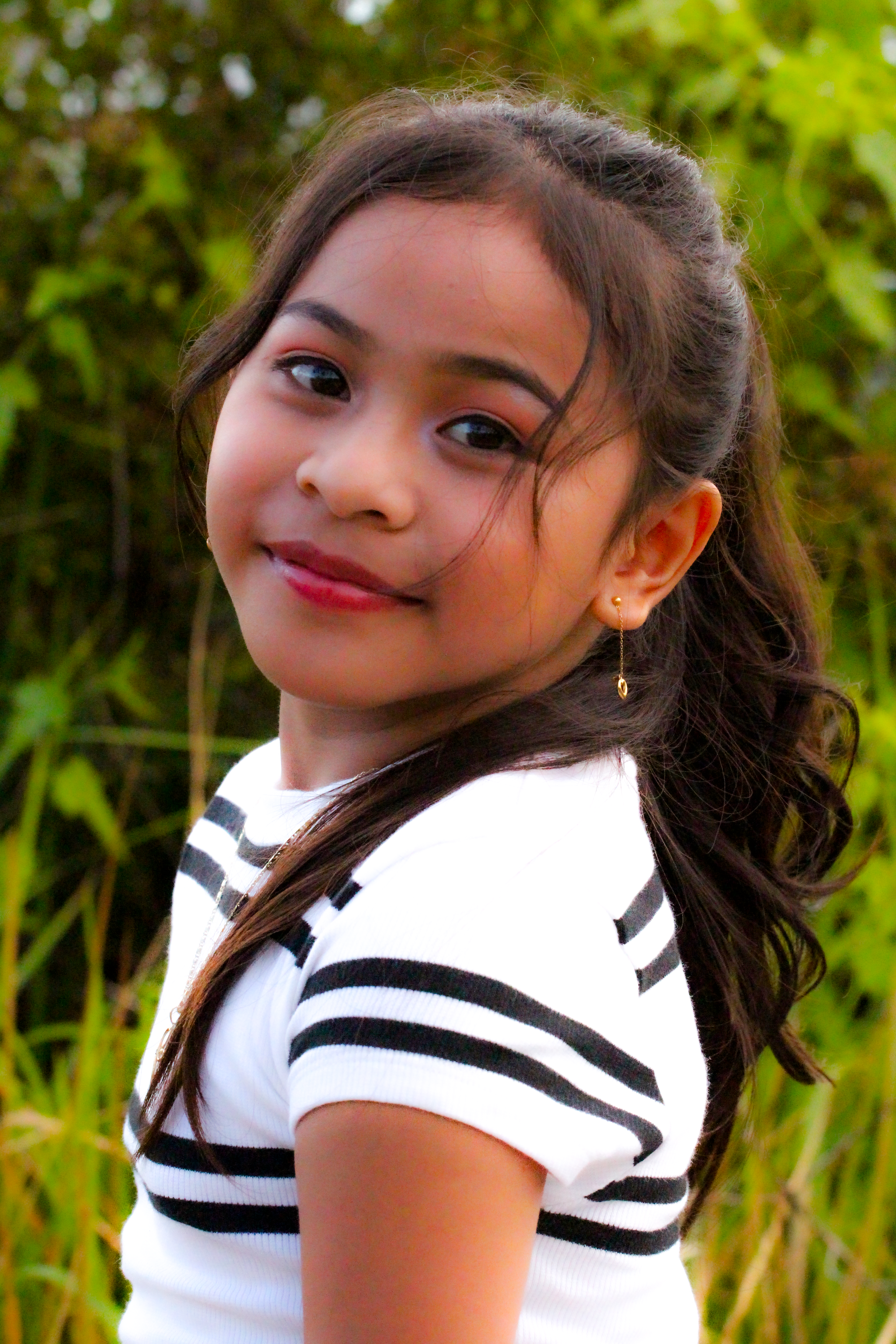 Charming portrait of a young girl smiling in a natural setting, showcasing innocence and joy.