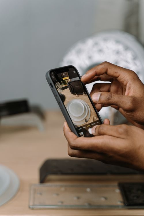 Free Hands using a smartphone to take a photo of elegant dinnerware indoors. Stock Photo