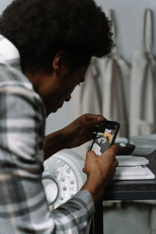 Free Black man taking smartphone photo of dining setup in cozy home interior. Stock Photo