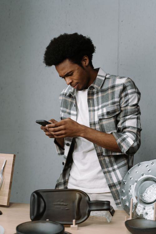 Free Young man interacting with a smartphone in a casual indoor setup. Stock Photo