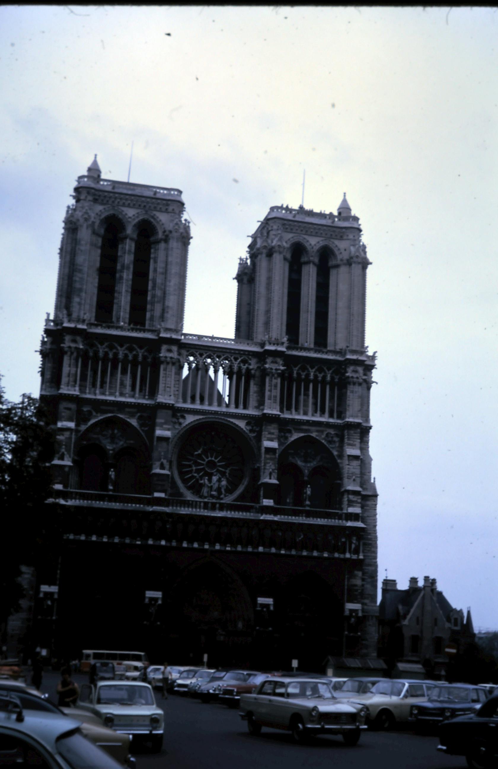 Historic Notre Dame Cathedral with vintage cars in foreground, Paris, France.