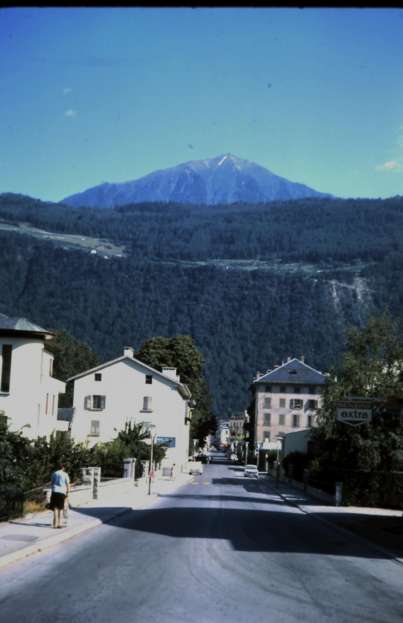 Scenic street view of an alpine village with mountain range in the background.
