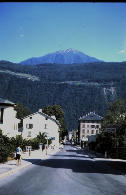 Scenic street view of an alpine village with mountain range in the background.