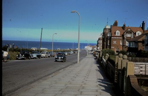 Free A nostalgic street scene featuring classic cars, historic buildings, and a clear ocean view. Stock Photo