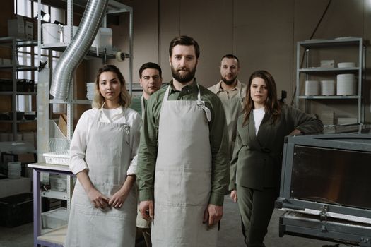 Group of professionals in aprons standing in an industrial workshop, showcasing teamwork.
