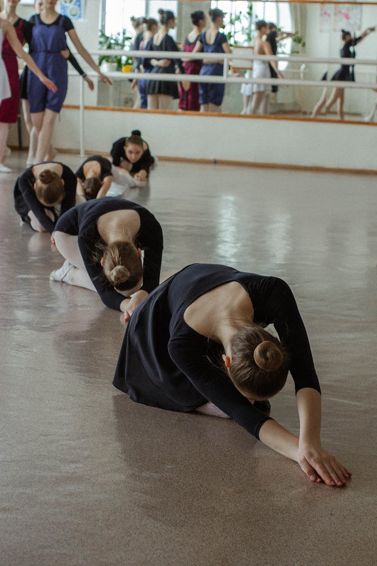 Anonymous Ballerinas Exercising On Floor In Dance Hall