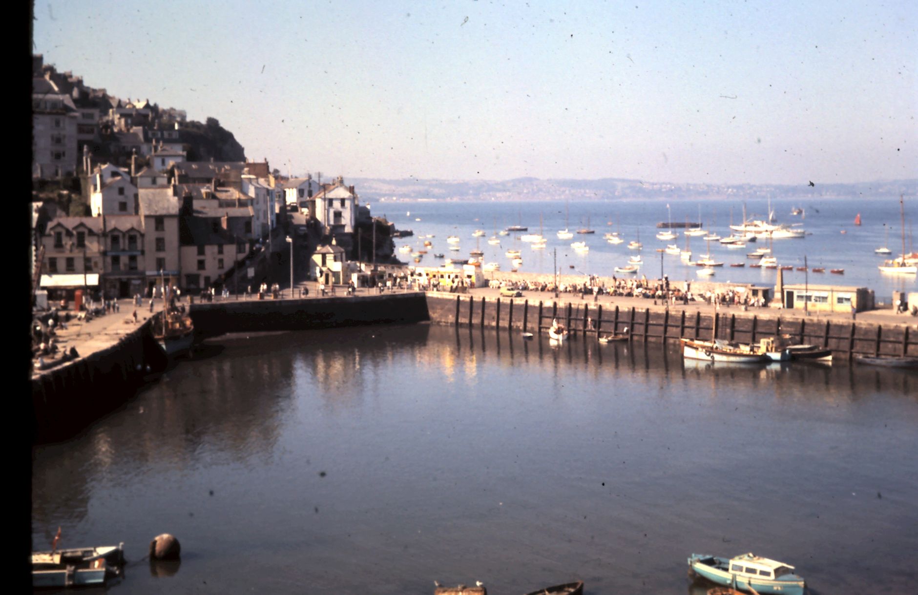 Colourful fishing boats moored in Brixham harbour, Devon, with the town rising behind