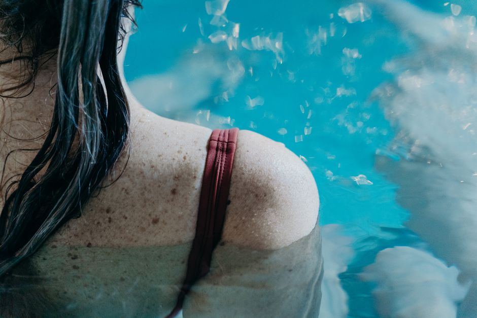 Close-up of woman's back with water droplets, emphasizing relaxation and summer vibes.