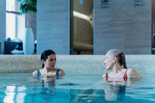 Free Two women enjoying a peaceful moment in an indoor pool setting. Stock Photo