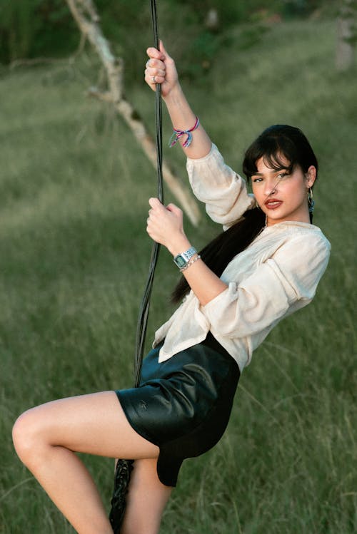 Stylish ethnic woman swinging in nature