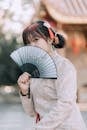 Shallow Focus of a Woman in Traditional Clothes Holding a Hand Fan