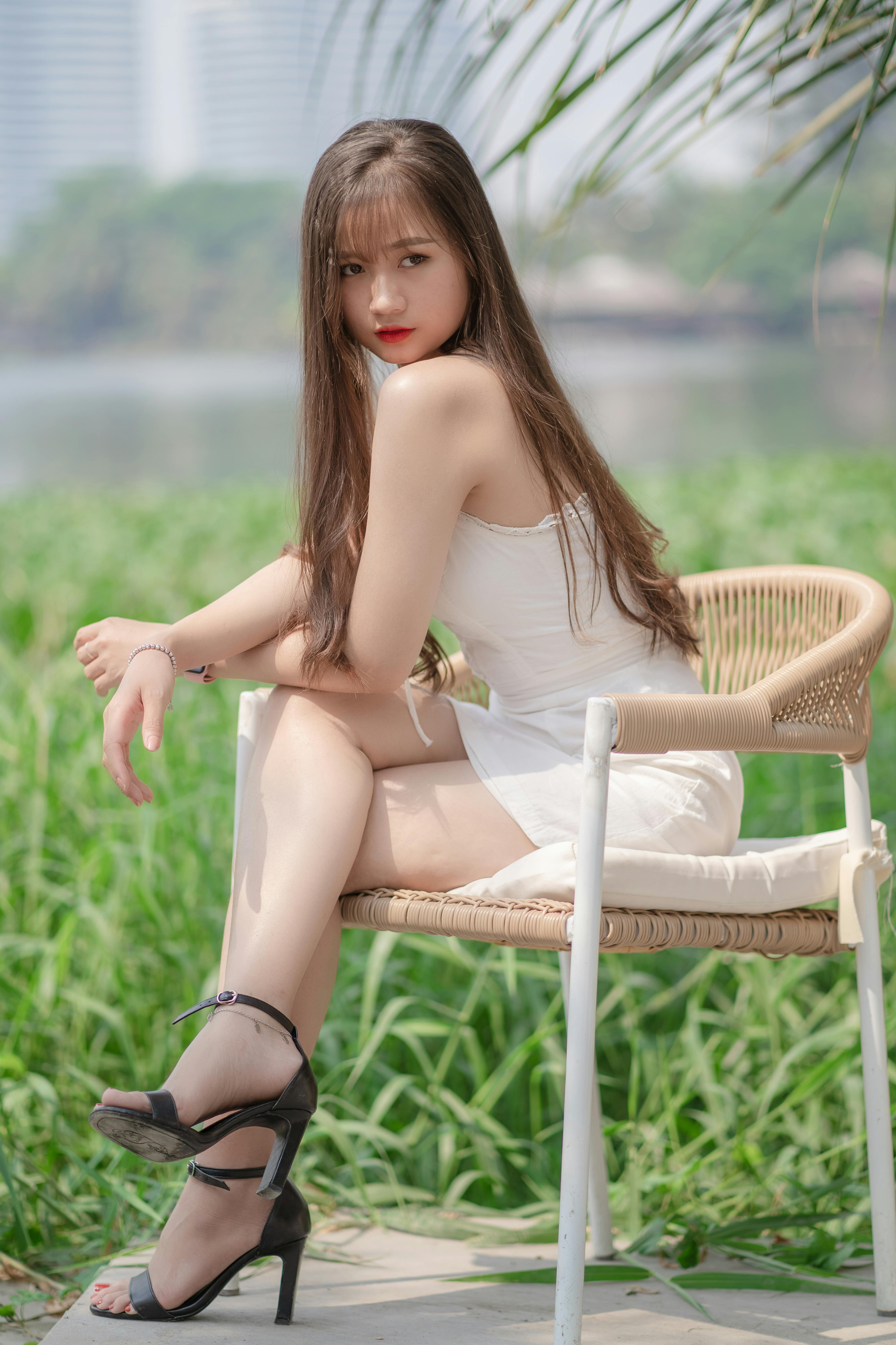 Young woman in a white dress posing stylishly outdoors in nature.