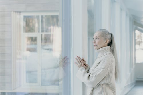 Free An Elderly Woman Looking through the Window Stock Photo
