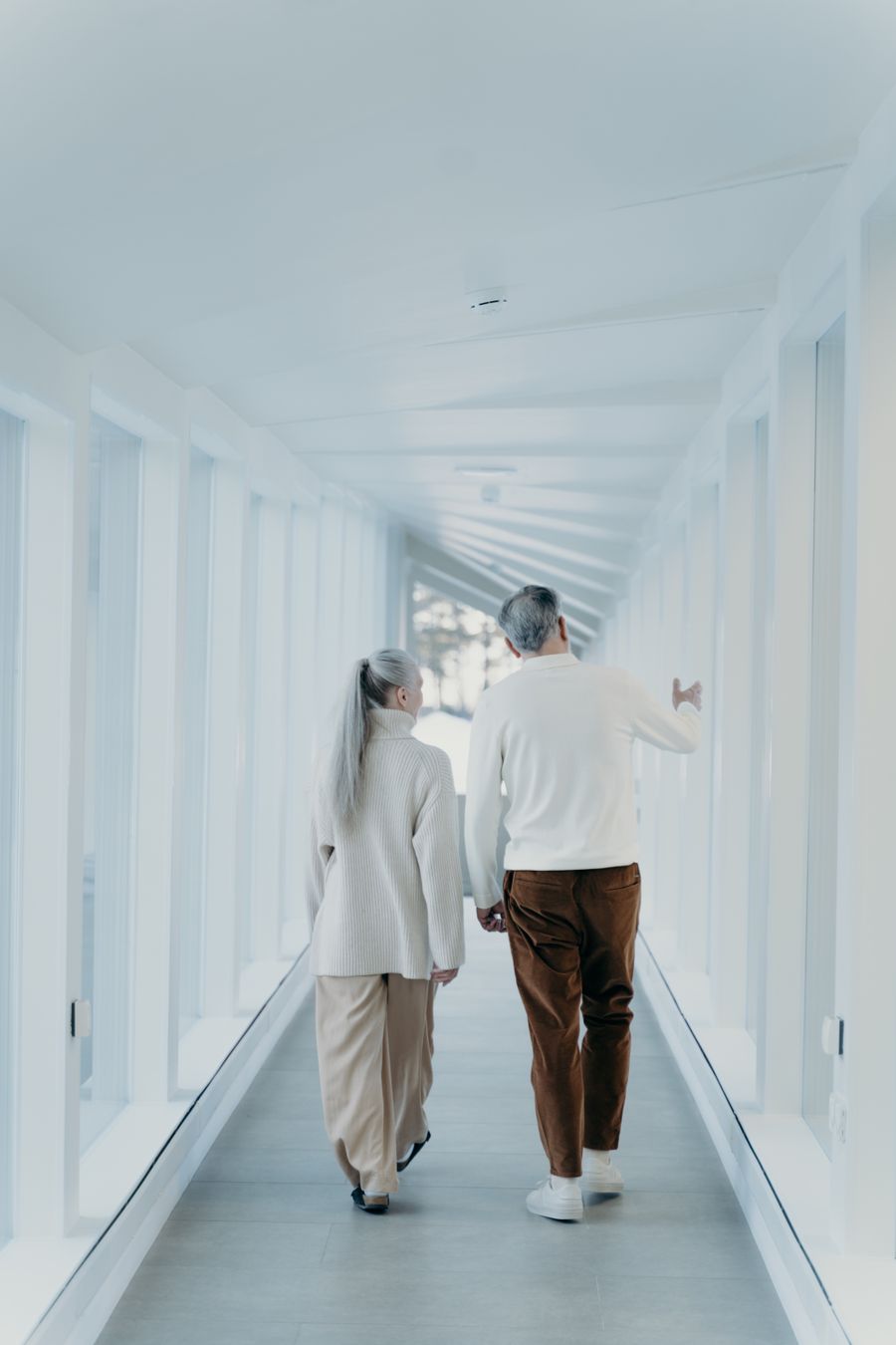 An older couple walking together along a bright indoor hallway
