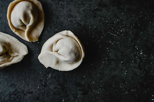 Close-up view of uncooked dumplings on a dark surface, capturing the texture and shape. Perfect for food photography enthusiasts.