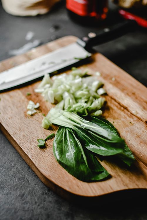 Free Close-up of fresh bok choy being chopped on a wooden board for cooking. Stock Photo