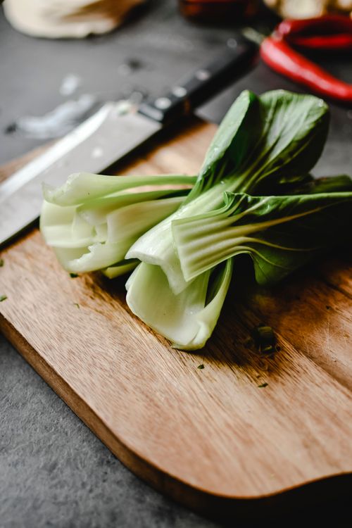 Free Close-up of fresh bok choy on a wooden chopping board with a knife nearby. Stock Photo