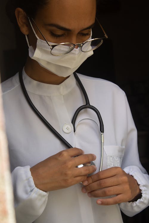 Woman in White Button Up Shirt Wearing Black Stethoscope and Face Mask