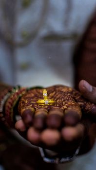 Gold and diamond rings held in a hand with elaborate mehndi design, conveying cultural elegance.