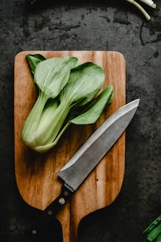 Vertical shot of fresh bok choy on a wooden board with a knife, perfect for food preparation concepts.