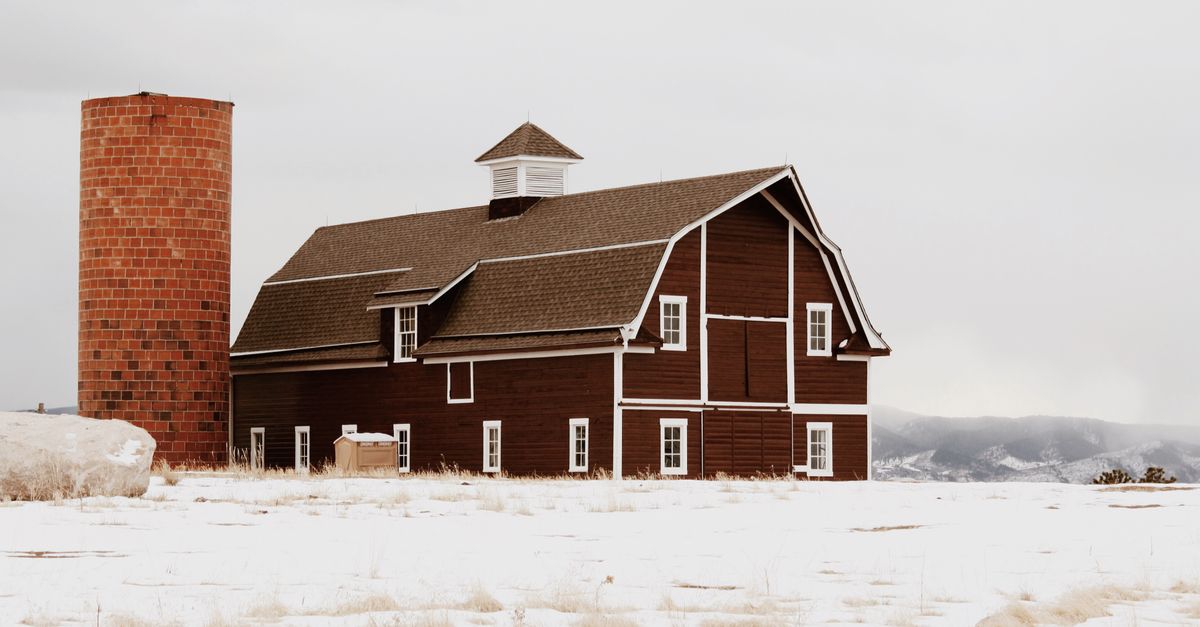 A charming red barn and silo stand amid a snowy winter landscape in Littleton, Colorado.