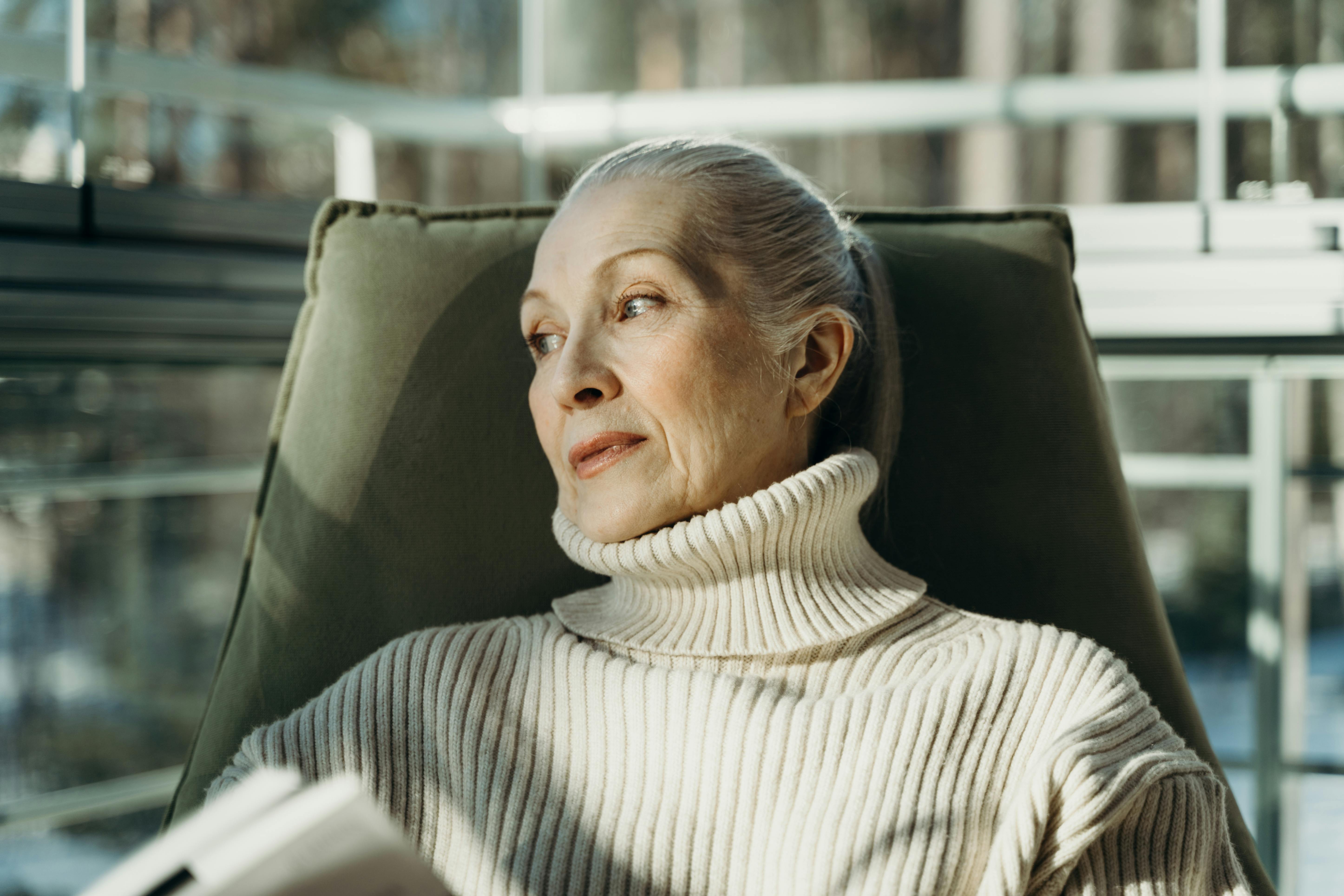 an elderly woman in turtleneck sweater sitting on a chair