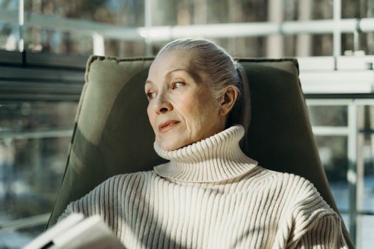 AN Elderly Woman In Turtleneck Sweater Sitting On A Chair