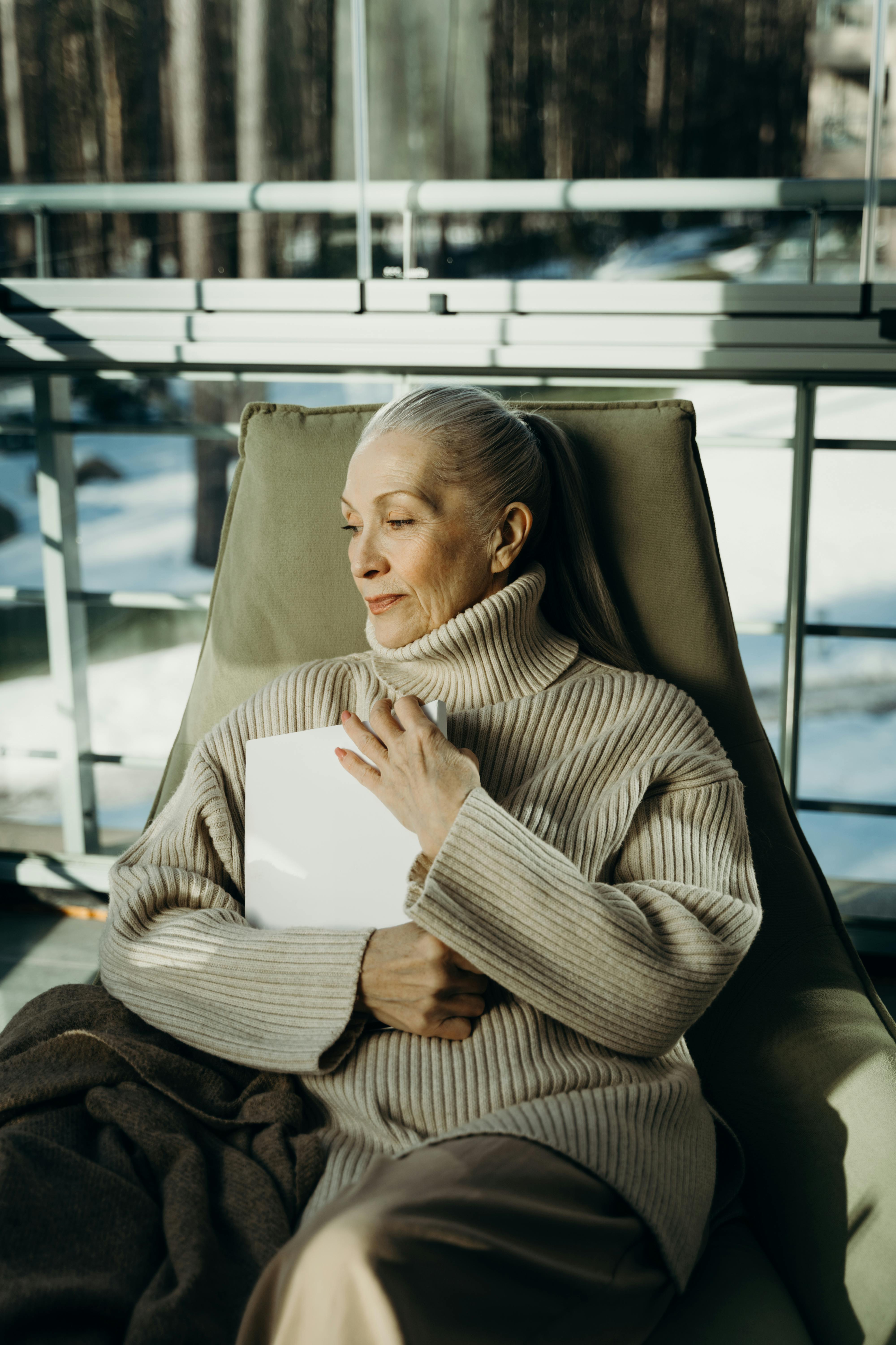 a woman holding a magazine while sitting on a brown armchair